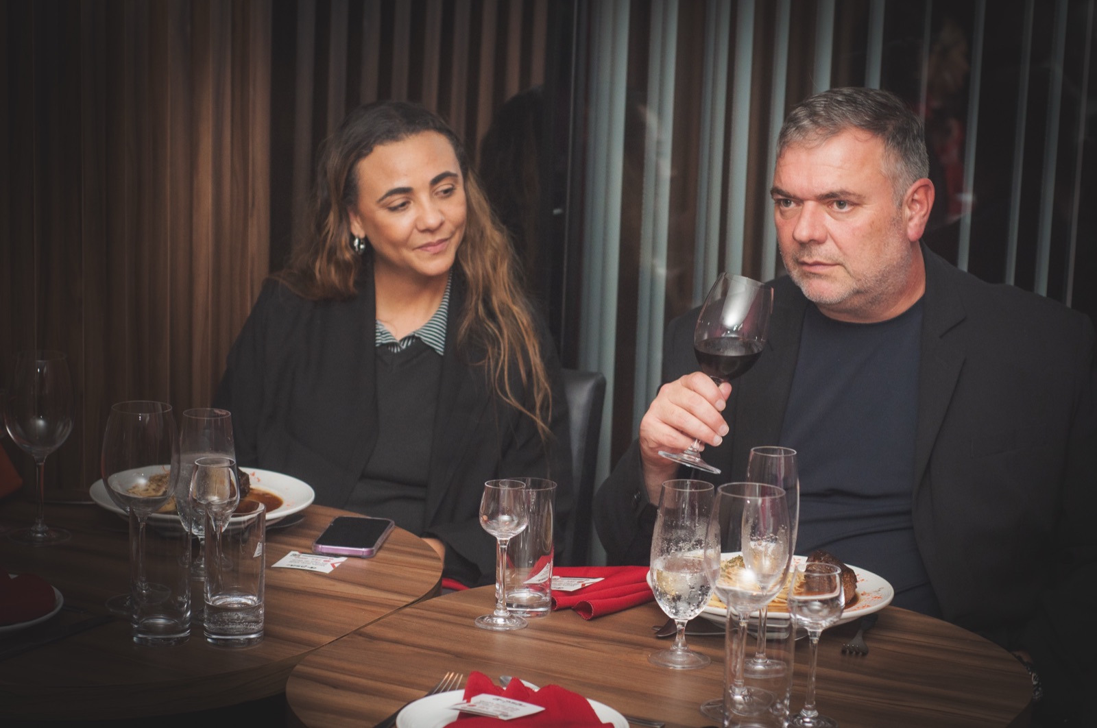 Convidados à mesa com taças de vinho durante o jantar do evento da Benner