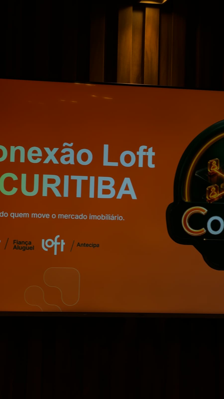 Telão exibindo a marca do Conexão Loft Curitiba no salão do El Vinos Gastrowine